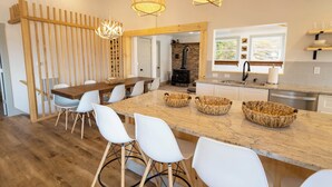 Una cucina moderna con una grande isola, sedie bianche e un tavolo da pranzo in legno.