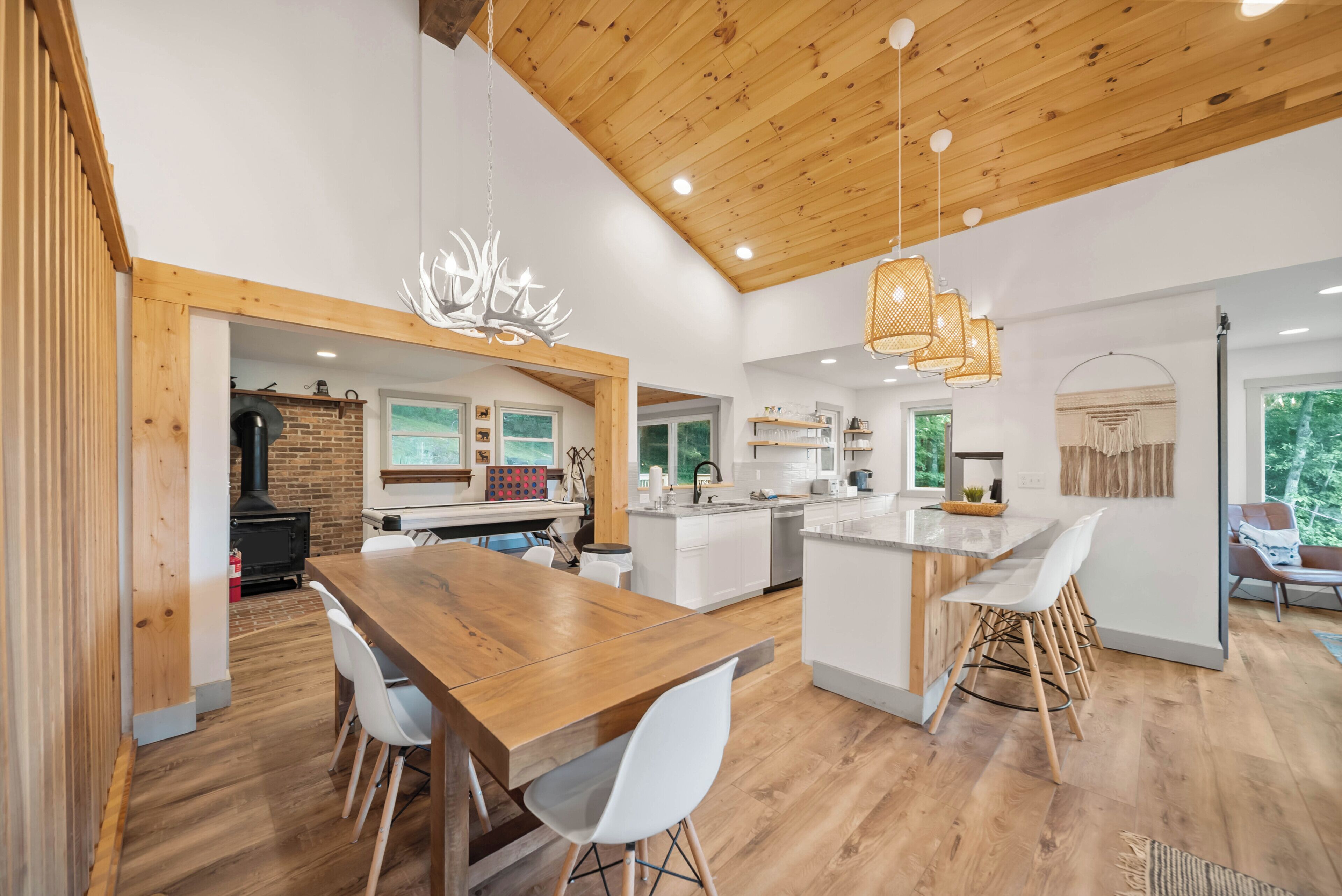 A modern kitchen with white cabinets, a wooden island, and a dining area with a wooden table and white chairs.