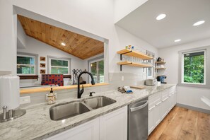 A modern kitchen with a large island, stainless steel appliances, and wooden ceiling beams. - A Red Chalet - Linville mountain chalet with game room, fireplace & year-round views (Newland)