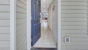 A hallway with a blue door, white walls, and a tiled floor. - Modern Beach Condo, Heated Pool Access (Tybee Island)