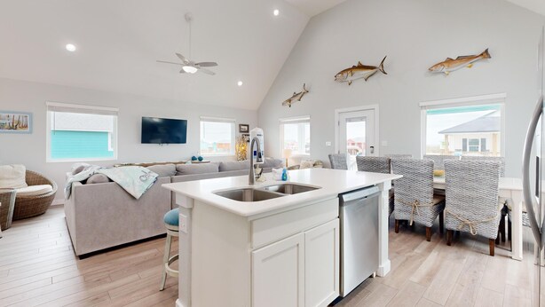 Un'ampia zona giorno con isola della cucina, tavolo da pranzo e ventilatore a soffitto.