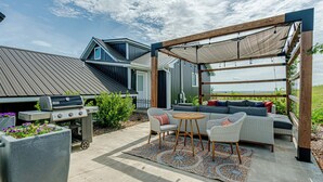 An outdoor patio with a grill, seating area, and a pergola providing shade. - Country Living with Modern Amenities and Hot Tub (Bismarck)
