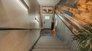 A staircase with a wooden wall, a door, and a welcome mat. - Country Living with Modern Amenities and Hot Tub (Bismarck)