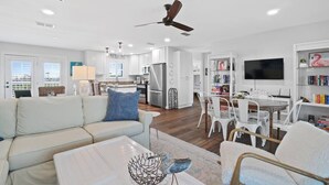 A modern living room with a sofa, coffee table, and a dining area with chairs and a table. - Sea 'n Stars Cape San Blas Vacation Rental (Port St. Joe)