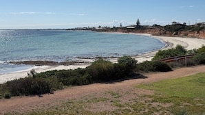 A coastal landscape with a beach, grassy areas, and a distant view of houses and a bridge. - Sleeps 14 - 3 minute walk to beach, 5 minute drive to "The Dunes" Golf Course  (Moonta Bay)