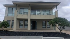 A two-story building with a balcony on the upper floor, a flat roof, and a small garden area with two trees. - Sleeps 14 - 3 minute walk to beach, 5 minute drive to "The Dunes" Golf Course  (Moonta Bay)