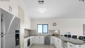 A modern kitchen with stainless steel appliances, white cabinetry, and a large window providing natural light. - Sleeps 14 - 3 minute walk to beach, 5 minute drive to "The Dunes" Golf Course  (Moonta Bay)