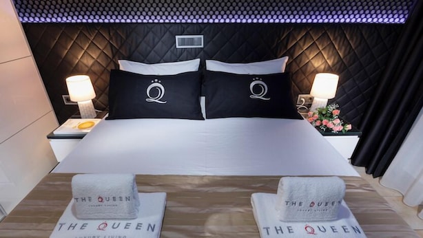 Une chambre d’hôtel avec un grand lit, deux oreillers ornés d’un monogramme, des tables de chevet avec des lampes et des serviettes portant le nom de l’hôtel.
