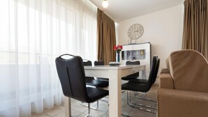 Un espace repas moderne avec une table blanche, des chaises noires et un canapé beige.