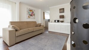 A modern living room with a beige sofa, a grey rug, and a white cabinet.