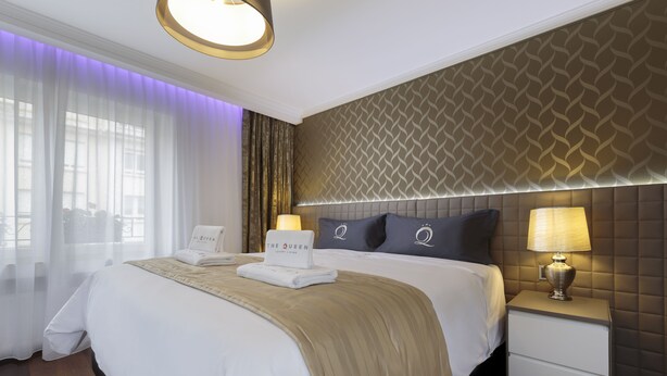 A hotel room with a large bed, a nightstand with a lamp, and a patterned headboard.