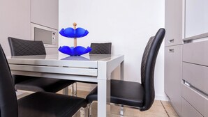 Un comedor moderno con una mesa blanca, sillas negras y un adorno azul.