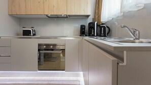 A modern kitchen with wooden cabinets, a built-in oven, a coffee maker, and a sink.