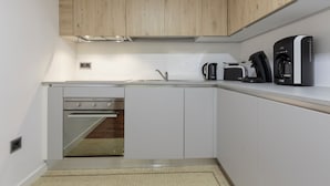 A modern kitchen with white cabinets, a built-in oven, a coffee maker, and a toaster.
