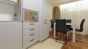 A compact kitchen with a microwave, a dining table with chairs, and a window with curtains.