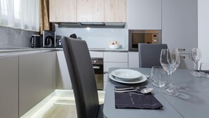 Una cocina moderna con armarios grises, una cafetera y un comedor con una mesa lista para dos.