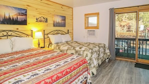 A room with two beds, wooden walls, a window with a view, and a balcony. - pacious Upper-Level Hotel Queen and Full-size beds with Views 208-210 (Estes Park)