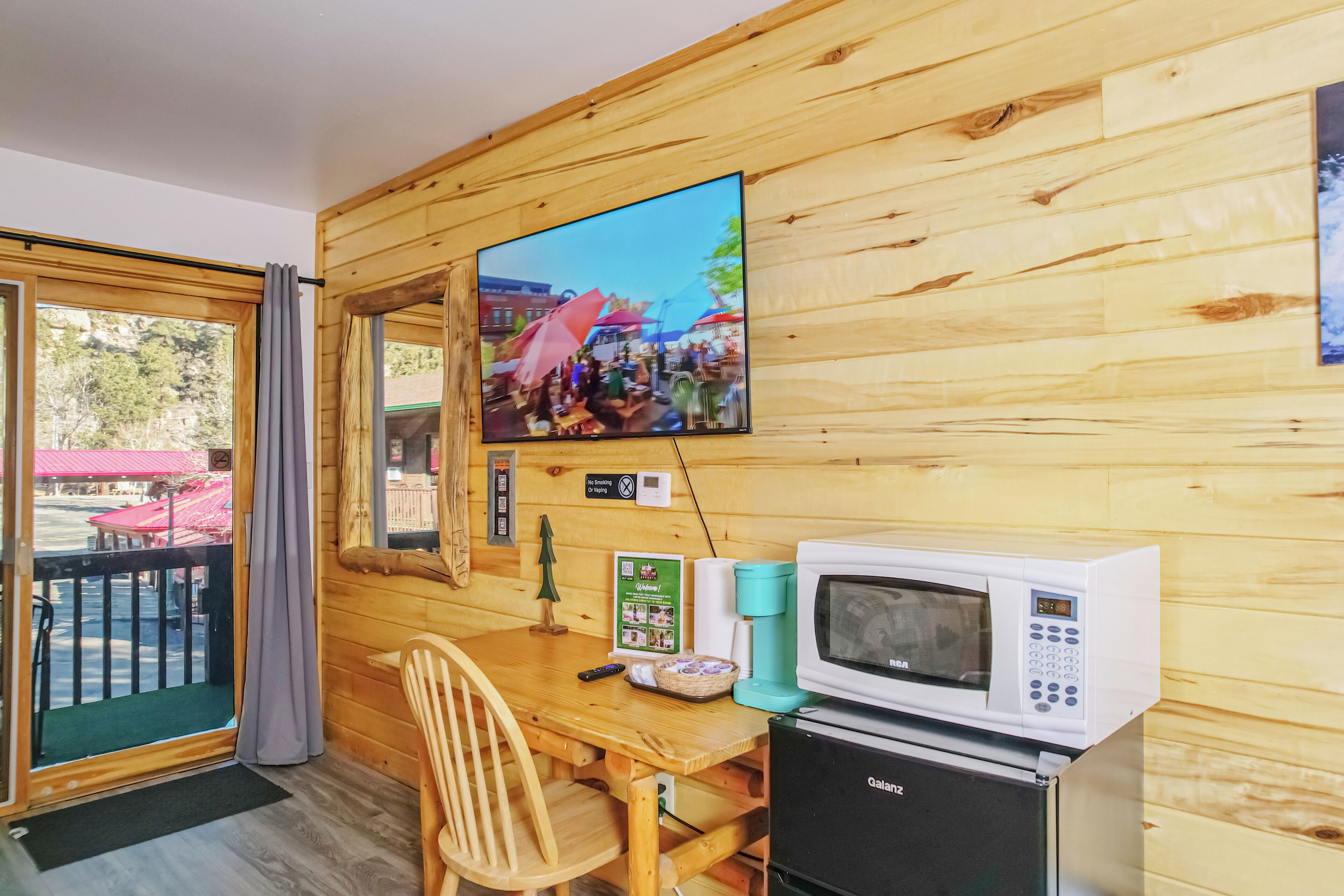 A wooden interior with a television, microwave, and a small refrigerator.