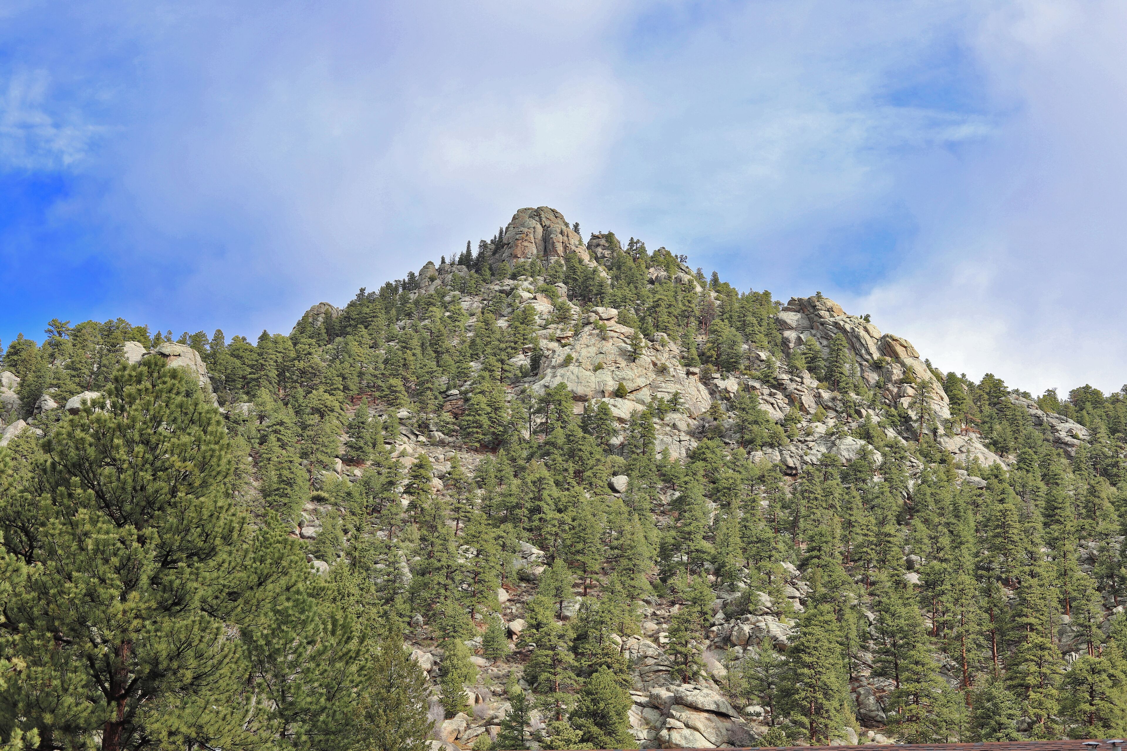 A mountain with dense forest and rocky terrain.