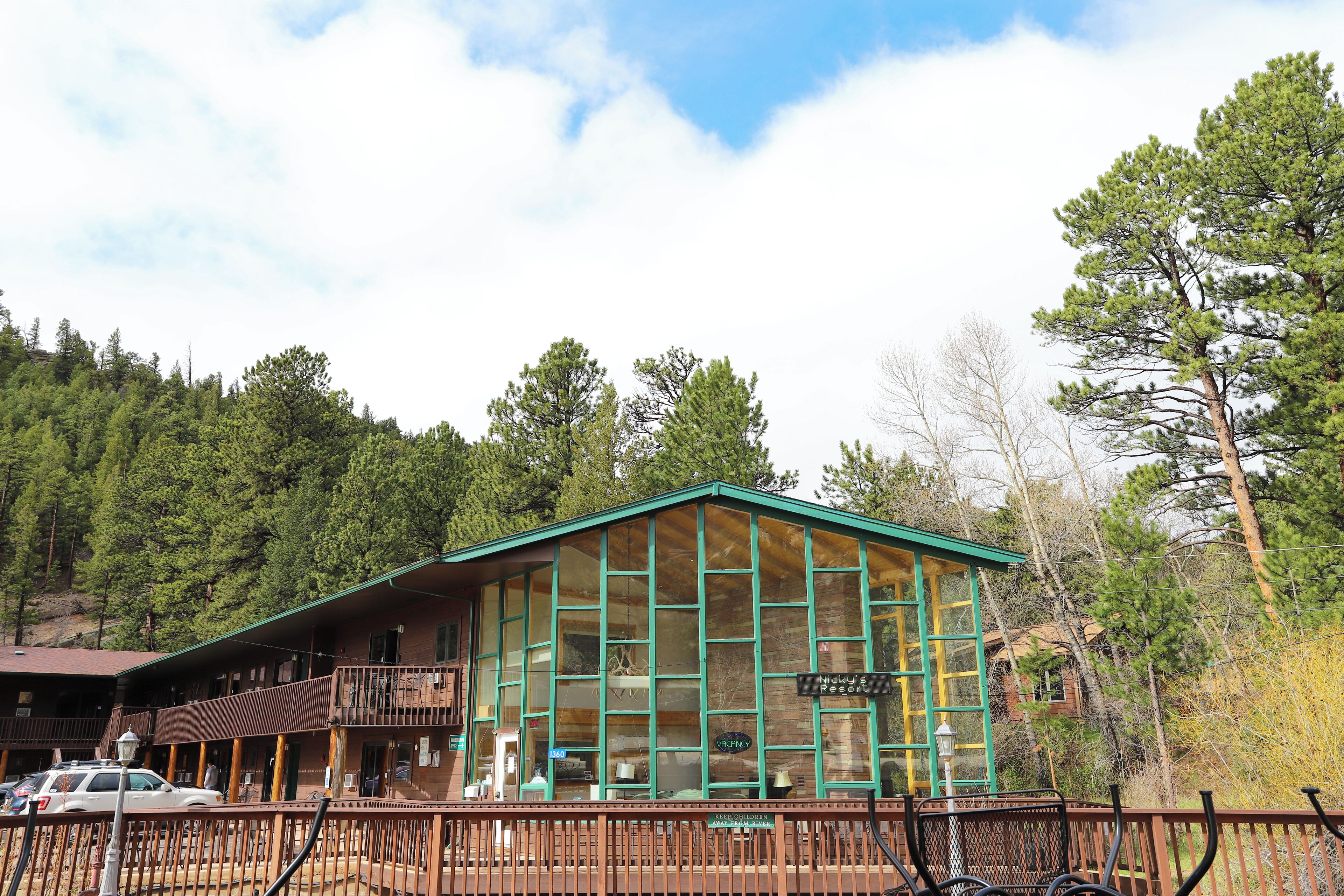 A lodge with a large glass facade, a balcony, and a sign reading "Nickey's Resort".