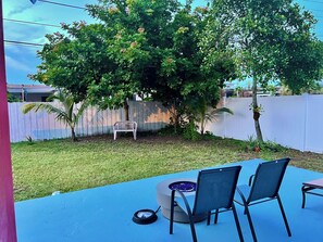 Relax in the serene backyard patio surrounded by lush trees and a beautifully manicured lawn.