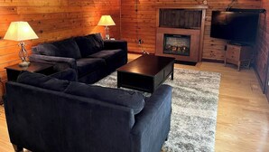 Una sala de estar acogedora con chimenea, dos sofás, una mesa de centro y un televisor.