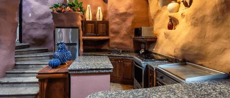A kitchen with granite countertops, a stainless steel refrigerator, and a built-in oven.