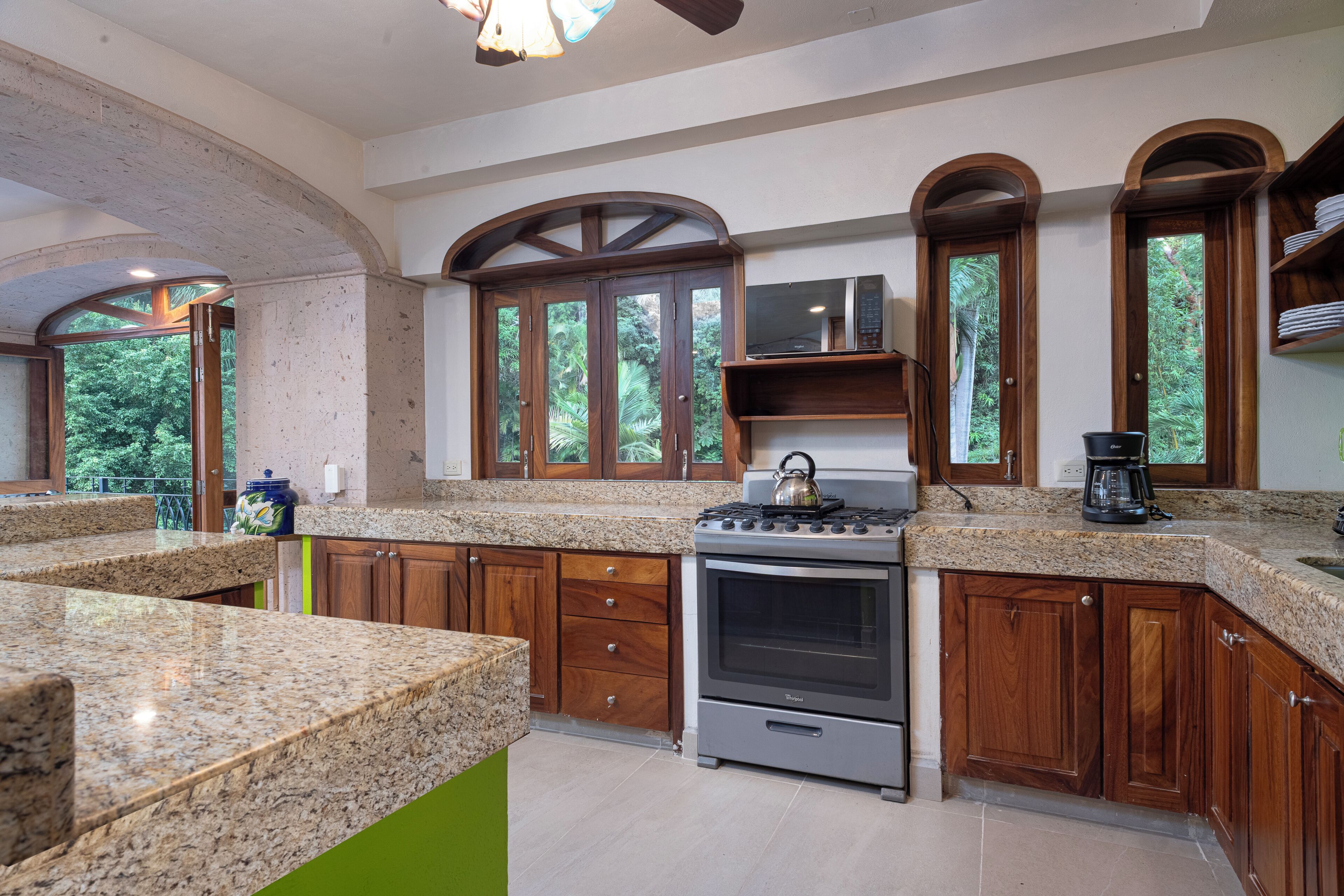 Una cocina con encimeras de granito, gabinetes de madera, estufa y cafetera.