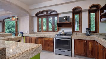 Una cocina con encimeras de granito, gabinetes de madera, estufa y cafetera.