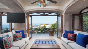 A balcony with a sofa, a table, and a TV. - Marcela Resort & Spa (Puerto Vallarta)