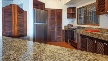 A kitchen with granite countertops, a stainless steel refrigerator, wooden cabinets, and a built-in oven.