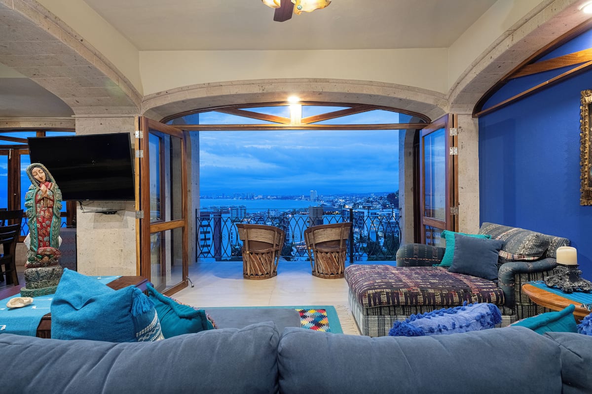 A living room with a city view, a television, and a statue.