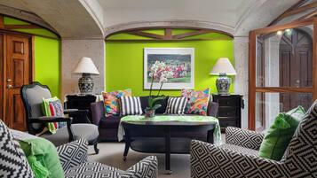 Un soggiorno con una parete verde, un divano nero, cuscini decorati, un tavolino da caffè e due lampade.