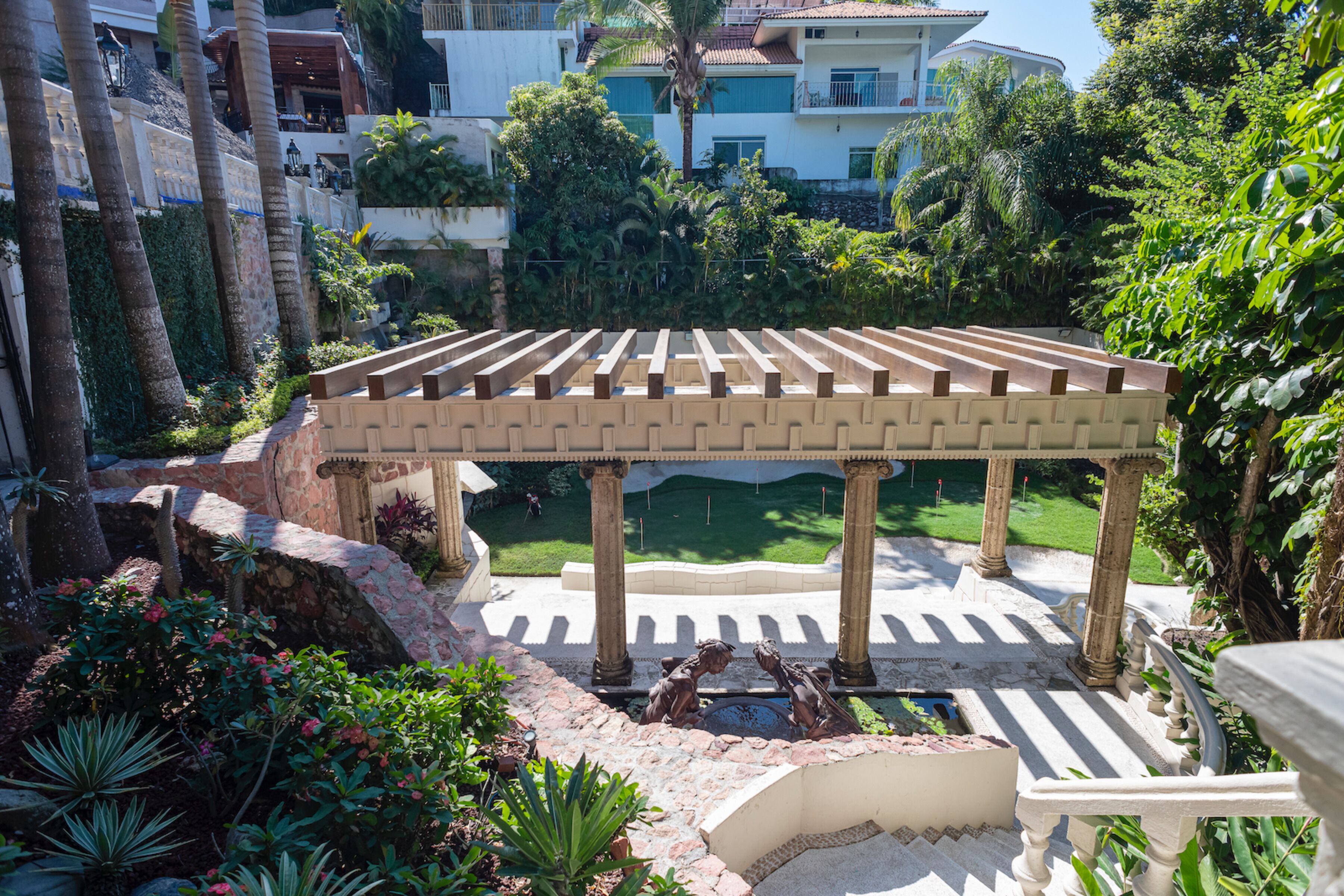 A covered outdoor area with a pergola, stone steps, and a small pool.