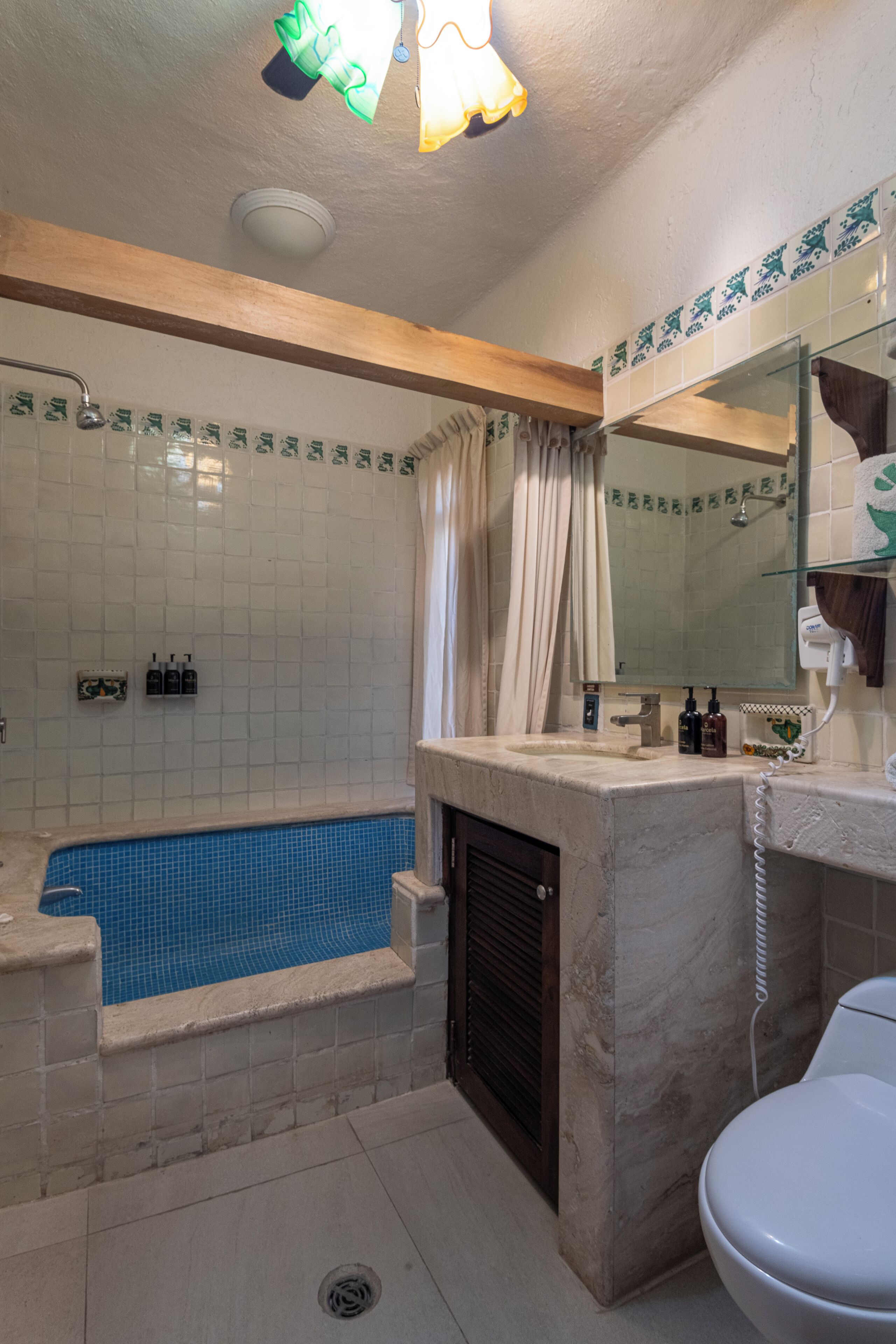 Une salle de bain avec un lavabo en marbre, une baignoire, des toilettes et une douche.