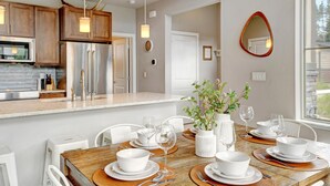 Una cocina moderna con armarios de madera, electrodomésticos de acero inoxidable e iluminación colgante.