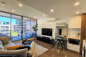Relax in this spacious living room with a large flat-screen TV, comfortable sofa, and dining area.