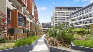 Un immeuble résidentiel moderne doté d’une cour intérieure agrémentée de jardinières et d’un sentier.