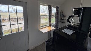 A compact kitchen with a coffee maker, a window with curtains, and a view of a yard. - Relax and still be close enough to the Newport Scene. (Portsmouth)