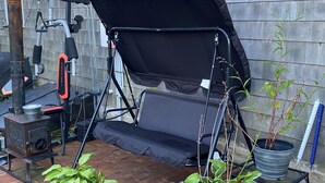 A patio with a swing seat, a grill, and potted plants. - Relax and still be close enough to the Newport Scene. (Portsmouth)
