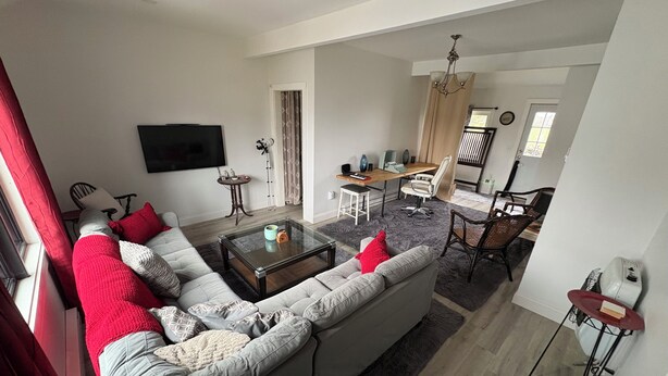 A living room with a sectional sofa, a coffee table, and a TV mounted on the wall. - Relax and still be close enough to the Newport Scene. (Portsmouth)