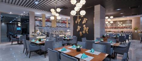 A modern restaurant with a long dining area, multiple tables, and chairs.