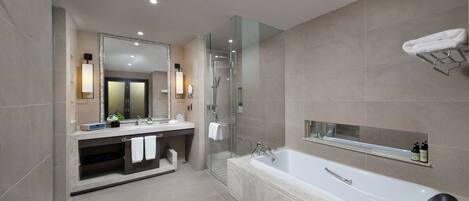 A modern bathroom with a large bathtub, a glass-enclosed shower, and a vanity with a mirror and lighting.