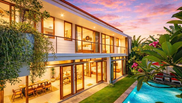 Una casa moderna de dos pisos con piscina, ventanas amplias y abundante vegetación.