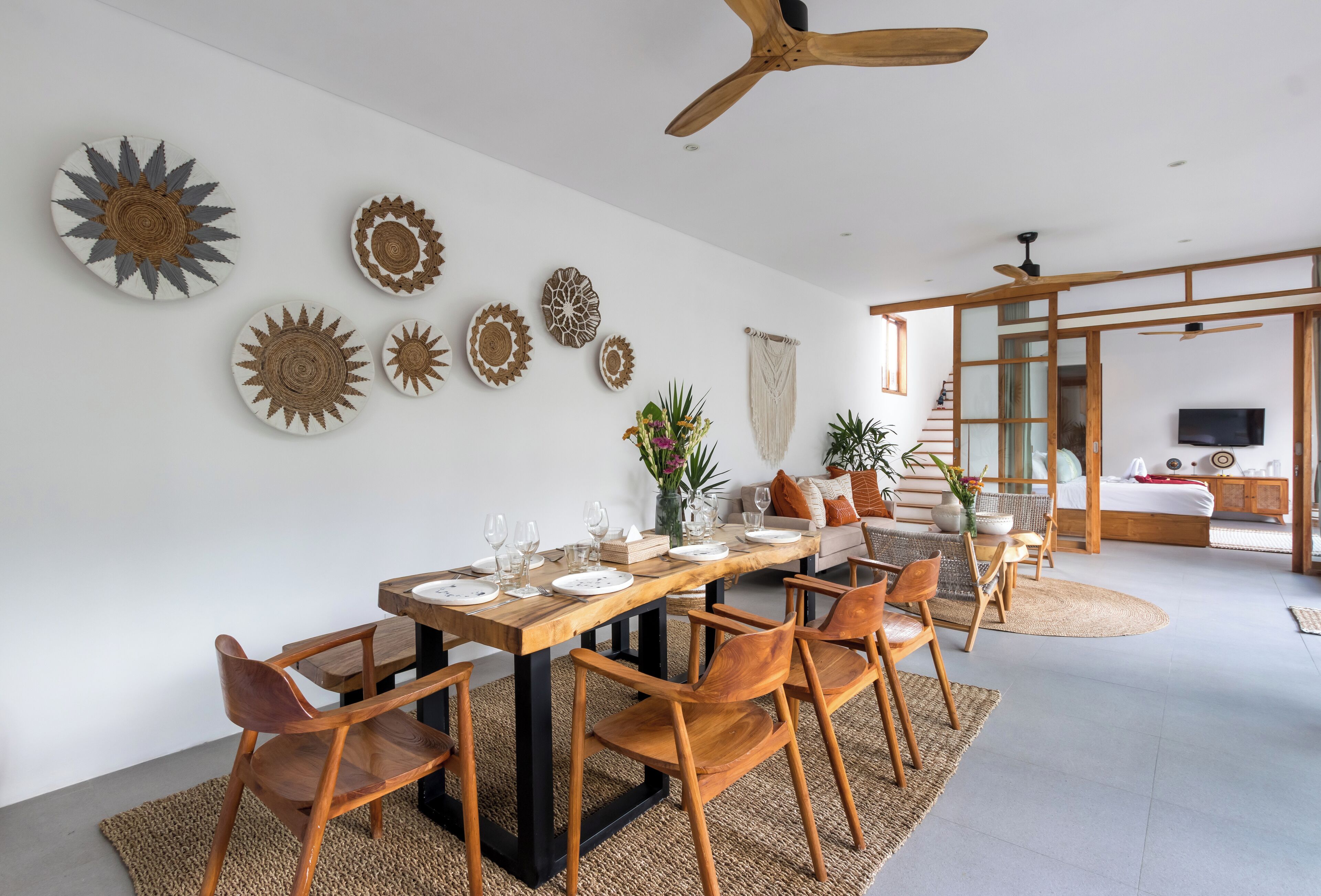 A modern dining area with a wooden table set for six, surrounded by wooden chairs.