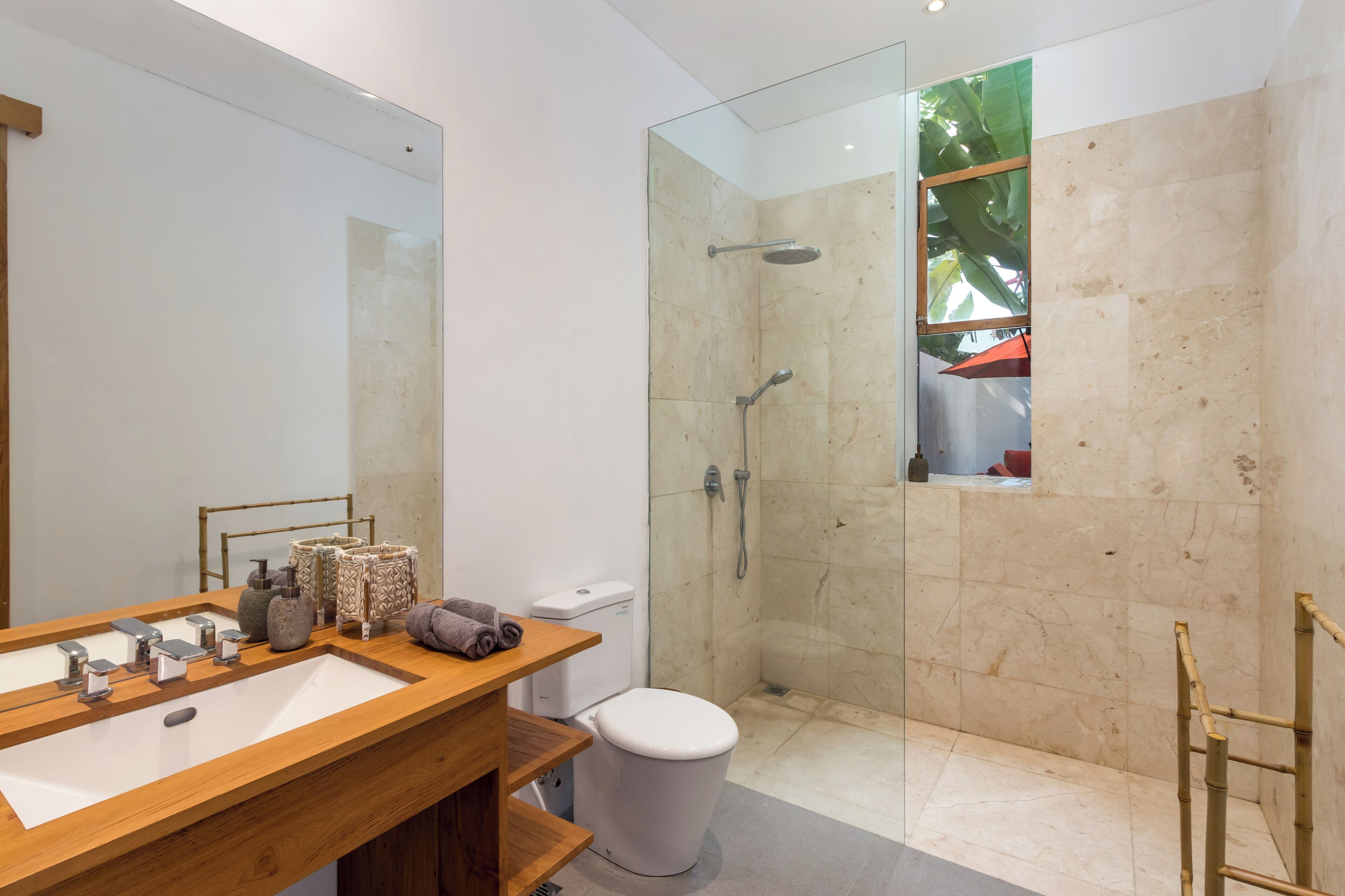A modern bathroom with a wooden vanity, a glass-enclosed shower, and a toilet.