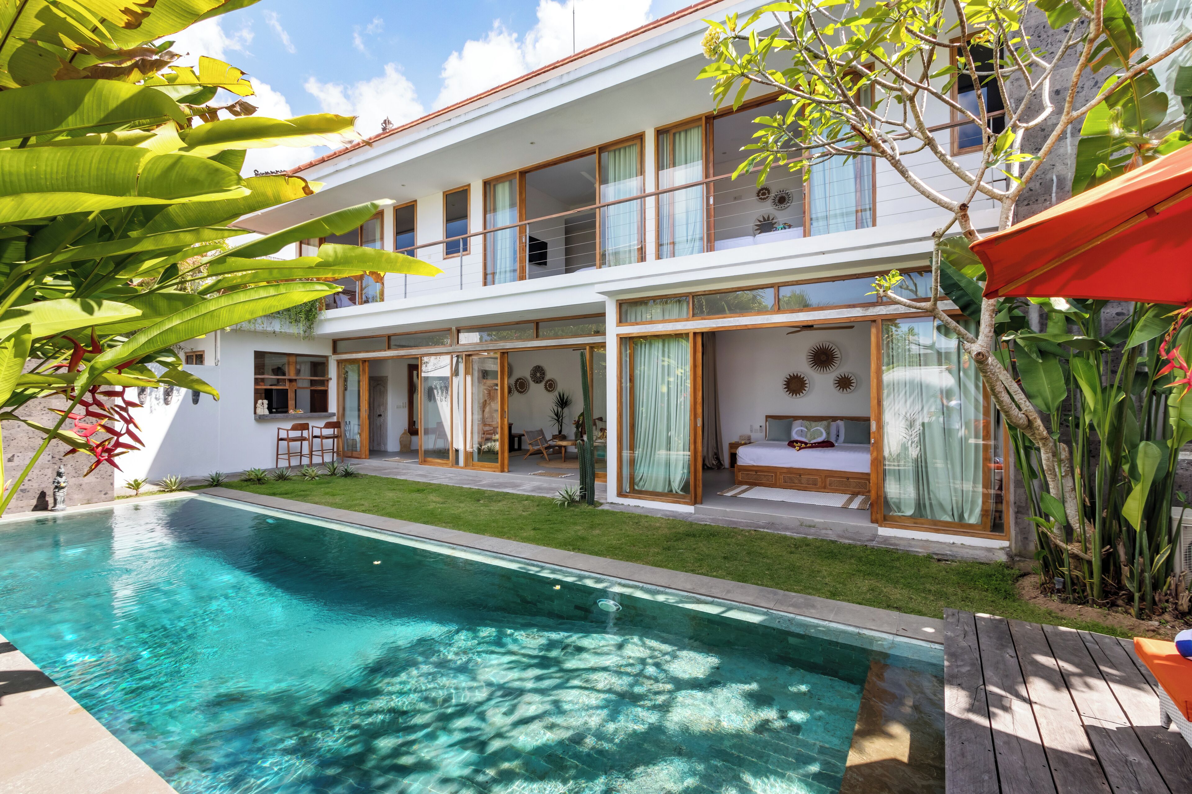 Une maison moderne à deux étages, dotée d’une piscine, de grandes fenêtres et d’un jardin bien entretenu.