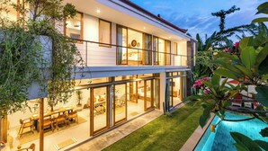 Una casa moderna de dos pisos con amplios ventanales, un comedor y una piscina.