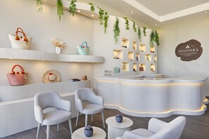 Un espace d’accueil doté d’un comptoir d’accueil incurvé, de deux fauteuils gris et d’une petite table ronde sur laquelle est posé un vase.