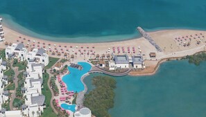 An aerial view of a resort with a large pool, beach area, and multiple buildings. - Anantara Mina Ras Al Khaimah Resort (Ras Al Khaimah)